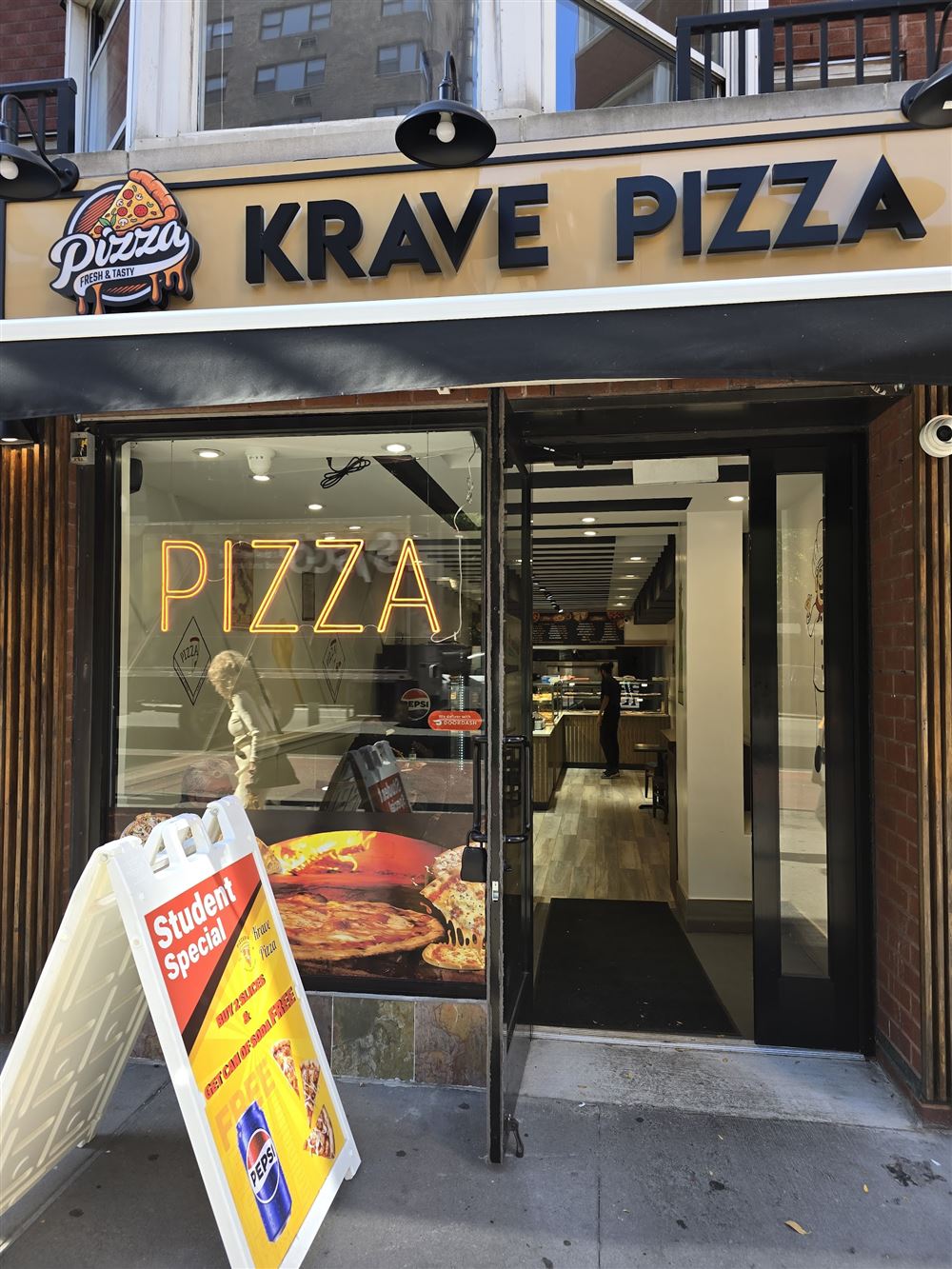 Krave Pizza storefront next door, with a glowing PIZZA neon sign in the window
